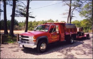 Green Acres Irrigation red service truck parked beside the trees