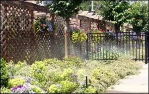 Spray heads watering a flower border along a lattice fence
