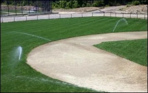 Sprinklers watering a baseball infield