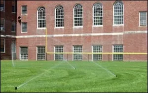 Sprinklers watering the lawn in front of a brick building