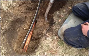Worker digging out and repairing buried irrigation pipe