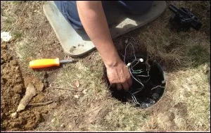 Worker wiring a valve box in the ground